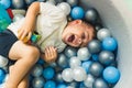 Happy toddler boy playing in a ball pit full of colorful balls. Sensory play at the nursery school for kids wellness