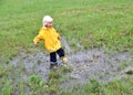 Happy toddler boy playing in a muddy puddle after the rain Royalty Free Stock Photo