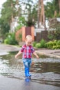 Happy toddler boy running through puddles in rubber boots. Child splashes after rain outside Royalty Free Stock Photo