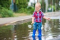 Happy toddler boy running through puddles in rubber boots. Child splashes after rain outside Royalty Free Stock Photo