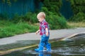 Happy toddler boy running through puddles in rubber boots. Child splashes after rain outside Royalty Free Stock Photo