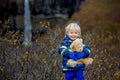 Happy toddler child, holding teddy bear, posing in front of beautiful waterfal Svartifossl in Skaftafell national park in Iceland Royalty Free Stock Photo