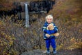 Happy toddler child, holding teddy bear, posing in front of beautiful waterfall Svartifoss in Skaftafell national park in Iceland Royalty Free Stock Photo