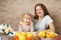 Happy toddler girl and her beautiful young mother making breakfast and eating fresh fruits together in a kitchen at home Royalty Free Stock Photo