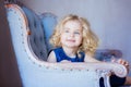 Happy toddler girl sitting in arm-chair. Smiling. Royalty Free Stock Photo