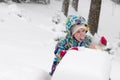 Happy toddler girl in warm coat and knitted hat tossing up snow and having a fun in the winter outside, outdoor portrait Royalty Free Stock Photo