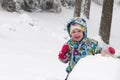 Happy toddler girl in warm coat and knitted hat tossing up snow and having a fun in the winter outside, outdoor portrait Royalty Free Stock Photo