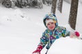 Happy toddler girl in warm coat and knitted hat tossing up snow and having a fun in the winter outside, outdoor portrait Royalty Free Stock Photo