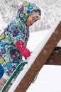 Happy toddler girl in warm coat and knitted hat tossing up snow and having a fun in the winter outside, outdoor portrait Royalty Free Stock Photo