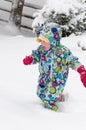 Happy toddler girl in warm coat and knitted hat tossing up snow and having a fun in the winter outside, outdoor portrait Royalty Free Stock Photo