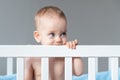 Happy toddler playing in crib, with a cute smile, exploring their world with nose, cheek, eye, eyelash, and thumb Royalty Free Stock Photo