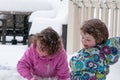 Happy toddler sibling girls in warm coat and knitted hat tossing up snow and having a fun in the winter outside, outdoor Royalty Free Stock Photo