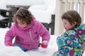 Happy toddler sibling girls in warm coat and knitted hat tossing up snow and having a fun in the winter outside, outdoor Royalty Free Stock Photo