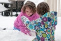 Happy toddler sibling girls in warm coat and knitted hat tossing up snow and having a fun in the winter outside, outdoor Royalty Free Stock Photo