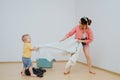 Happy toddler son and his mother are playing tug of war with towel