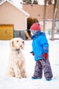 Happy toddler white Caucasian boy running and playing with snow and white large big pet dog