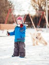 Happy toddler white Caucasian boy running and playing with snow and white large big pet dog