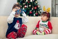 Happy toddlers boys playing with Christmas tree in the background