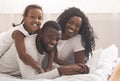 Black parents and their daughter lying on bed using laptop Royalty Free Stock Photo