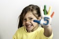 Happy toothless little girl with the five number painted on the hand laughing and having fun - Little girl who is painting her Royalty Free Stock Photo