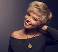 Happy toothy smiling woman with short blond bob hairstyle in grey blouse and orange fashion necklace on gray background. Closeup Royalty Free Stock Photo