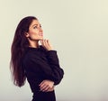 Happy toothy thinking smiling brunette woman looking up in blank black shirt with hand under the face on blue background with