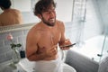 Happy topless man texting while brushing teeth