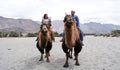 A happy tourist couple riding on double humped Bactrian camels