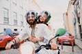 Happy tourist couple in protective hats are riding on rental vintage scooter in the Lisbon street Royalty Free Stock Photo