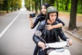 Happy tourist young couple on scooter ride in new city. Woman making photo on camera while riding outdoors Royalty Free Stock Photo