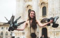 Happy tourist in front of Duomo cathedral, Milan, Milano. Funny girl with dove sitting between them. Doves eats feed
