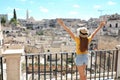 Happy tourist girl with arms raised up enjoys the stunning view of the Sassi di Matera in Italy on a warm summer day. Travel Royalty Free Stock Photo