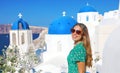 Happy tourist girl enjoying travel in Greece. Beautiful tanned woman with sunglasses visiting Oia village in Santorini island, Royalty Free Stock Photo