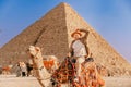 Happy Tourist man with hat riding on camel background pyramid of Egyptian Giza, sunset Cairo, Egypt Royalty Free Stock Photo