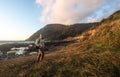 Happy tourist man walk and hike on ocean trail near mountains at sunset time Royalty Free Stock Photo