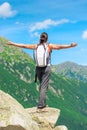 A happy tourist is standing by the cliff at the edge of the rock