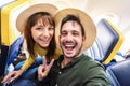 Happy tourist taking selfie inside airplane - Cheerful couple on summer vacation - Passengers boarding on plane Royalty Free Stock Photo