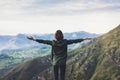 Happy tourist traveler standing on a rock with raised hands, hiker looking to a valley below in trip in spain, hipster young girl Royalty Free Stock Photo