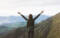 Happy tourist traveler standing on a rock with raised hands, hiker looking to a valley below in trip in spain, hipster young girl Royalty Free Stock Photo