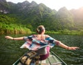 Happy tourist travels by boat on river amidst the scenic green mountains