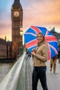 A tourist woman with a british flag umbrella stands in front of the Big Ben tower at Westminster in London, UK Royalty Free Stock Photo