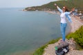 Happy tourist woman climbed to the top of the mountain. Emotions of joy and happiness. Mountain and sea in the background