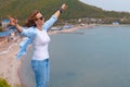 Happy tourist woman climbed to the top of the mountain. Emotions of joy and happiness. Mountain and sea in the background. Close