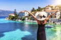 A happy tourist woman with hat looks to the idyllic village of Fiscardo