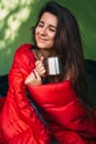 A happy tourist woman is sitting in a tent and drinking tea. Camp in the tent - young girl on the camping. Royalty Free Stock Photo