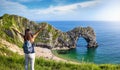 A happy tourist woman stands in front of the famous Durdle Door beach Royalty Free Stock Photo