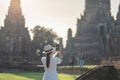 Happy tourist woman in white dress taking Photo by mobile smartphone, during visiting in Wat Chaiwatthanaram temple in Ayutthaya Royalty Free Stock Photo