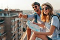Happy tourists couple, friends sightseeing city with map together. Travel people concept. Royalty Free Stock Photo