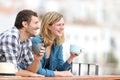 Happy tourists drinking coffee and sightseeing in a balcony