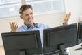 Happy Trader Gesturing While Using Multiple Screens At Desk